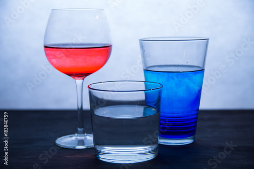 Three glasses of colored water on a white and blue background