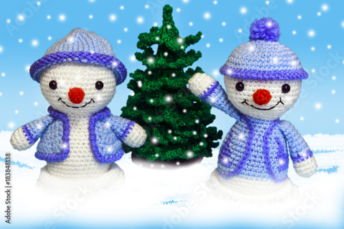 two cheerful snowman toy in the snow near the Christmas tree