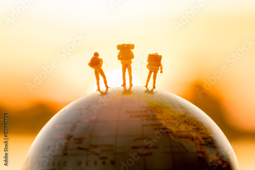 Foto miniature figure people  backpack standing on globe with sunset or sunrise sky b