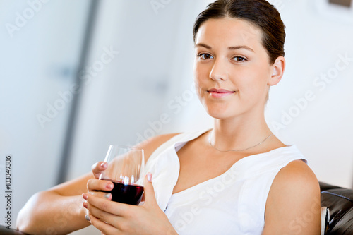 Beautiful young woman holding glass with red wine