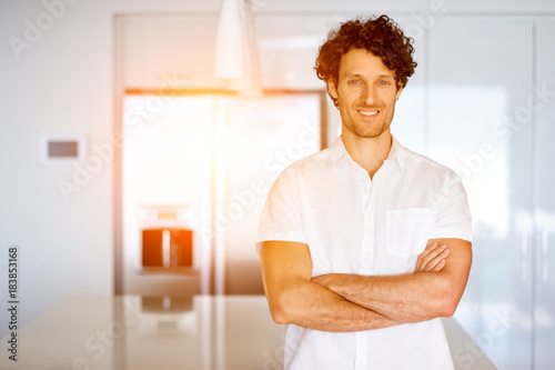 Portrait of a smart young man standing in kitchen photo
