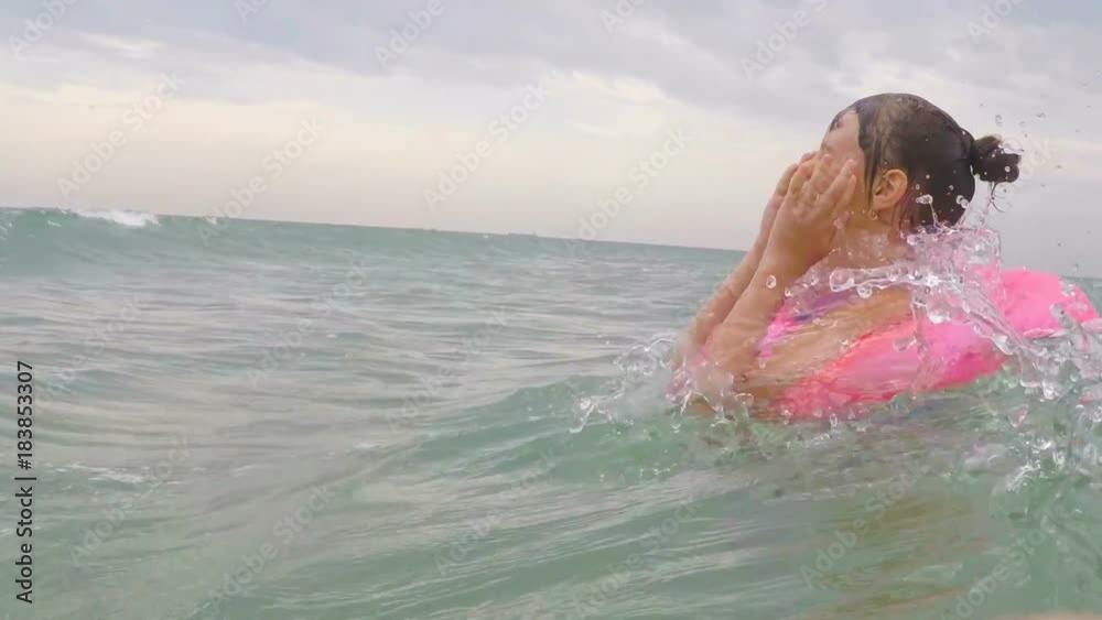 The child swims on the waves. A happy little girl on an inflatable circle is floating on the waves. The child swims on the waves. A happy little girl on an inflatable circle is floating on the waves.