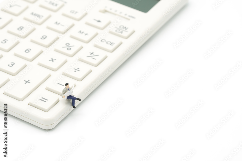 Miniature people read newspaper sitting on white calculator using as background business concept with copy space. Miniature people read newspaper sitting on white calculator using as background business concept with copy space.