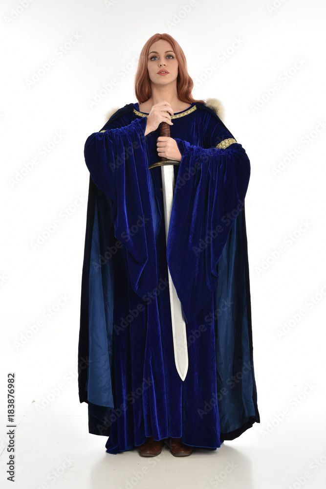  full length portrait of girl wearing long blue velvet gown and fur lined cloak, standing pose  on white background.