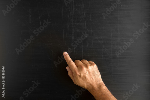 Hand holding a chalk and writing something against blackboard with copy space on blackboard