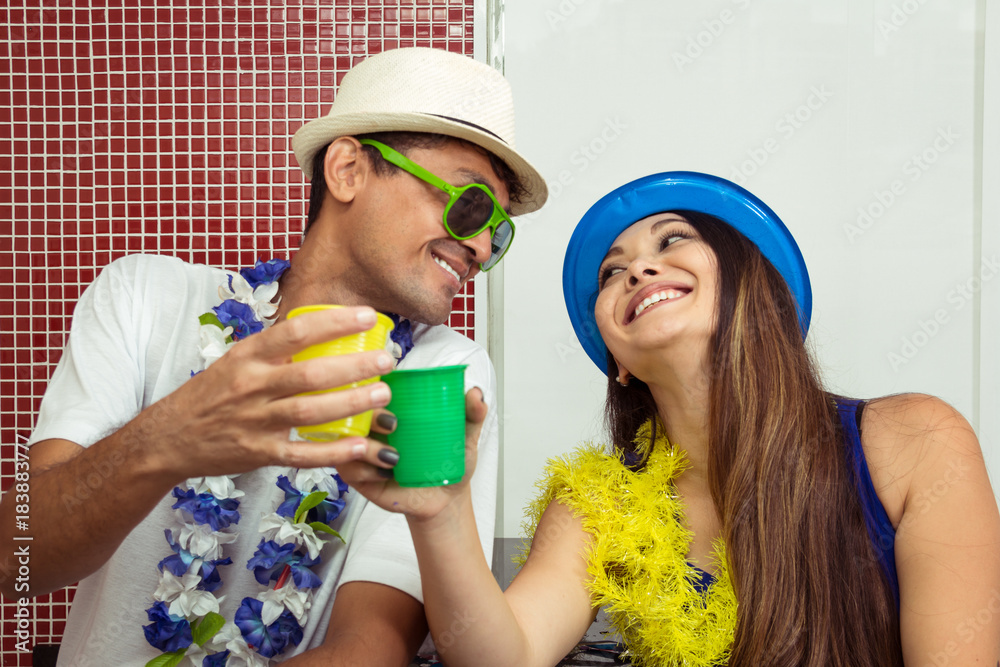 Multi ethnic couple is celebrating the Brazilian Carnaval. Friends are toasting at the party..
