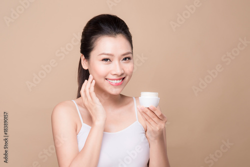 Skincare. Beautiful asian woman show moisturizer or lotion product.