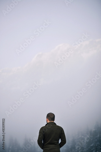 Hiker contemplating in front of foggy forest landscape