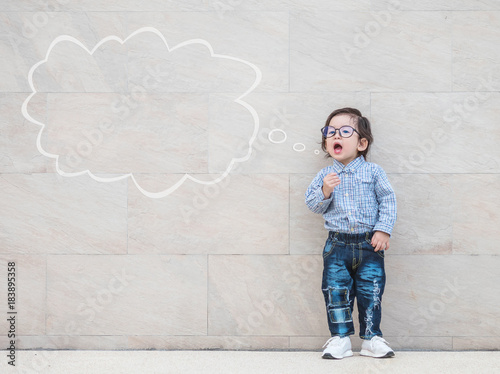 Closeup asian kid say something action with text box on marble stone wall textured background with copy space photo