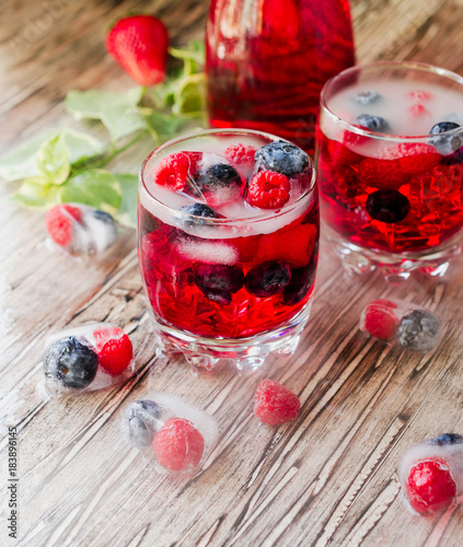 Summer berry lemonade with frozen berries on a wooden rustic table, selective focus photo