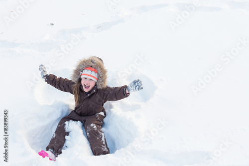 Beautiful little girl playing in freshly fallen snow in winter park