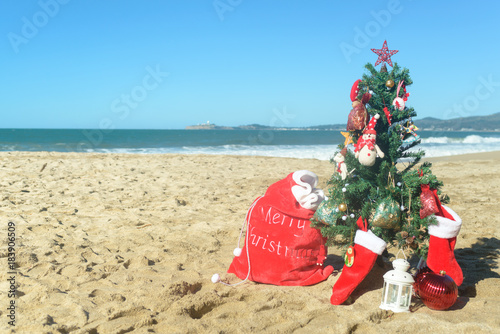 Christmas tree and red Santa bag of presents at the beach