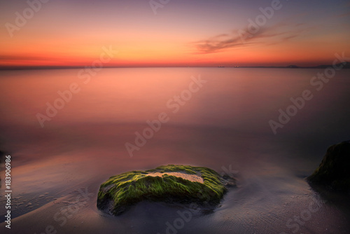 A rock overgrown with beautiful green algae in the hug of sunrise © Todor