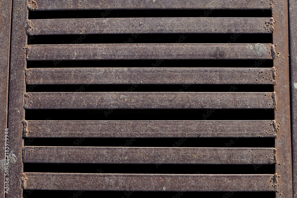 Close up of rusty iron grate on the road.