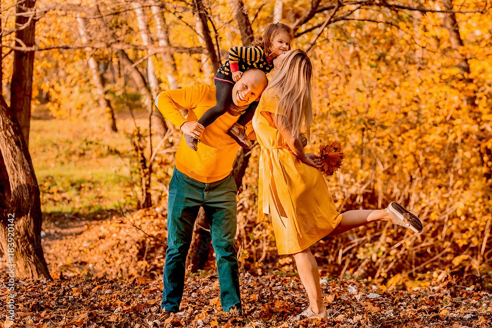 Naklejka premium The father holds on shoulders his daughter and mother kiss her daughter