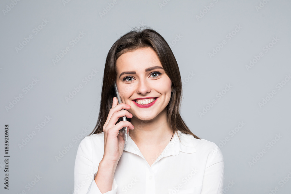 Portrait of a happy lovely woman talking on the phone and looking at camera on a white background