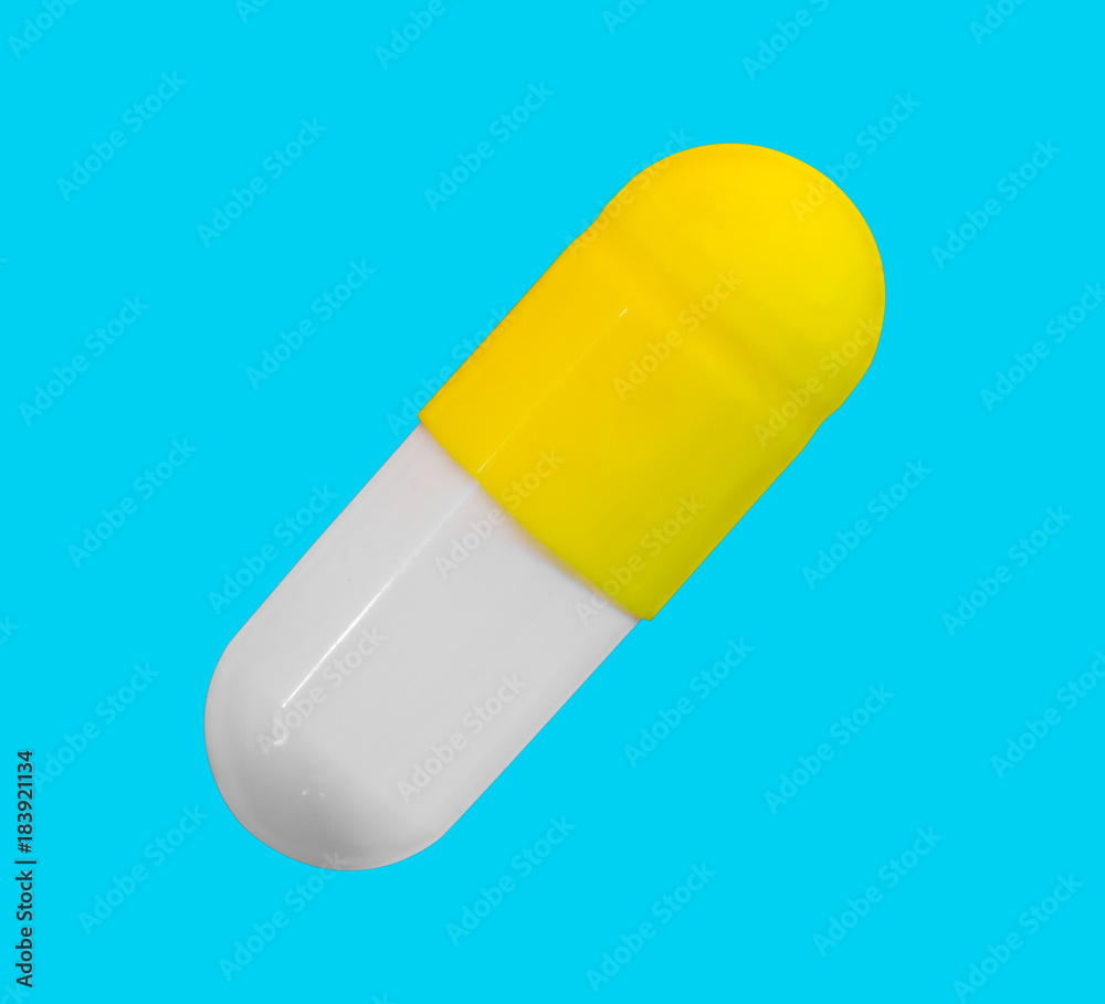 a gelatin capsule with yellow cap isolated on a blue background closeup, top view a gelatin capsule with yellow cap isolated on a blue background closeup, top view