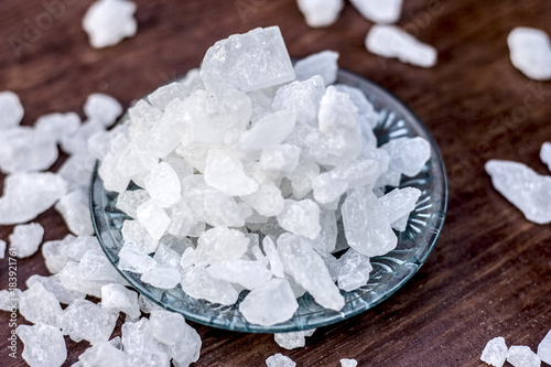 Rock sugar or sugar cubes in a glass plate on wooden surface.