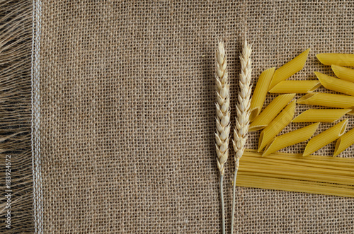 Still life for a kitchen of wheat ears and pasta from wheat on a sackcloth background. Made in Kazakhstan photo