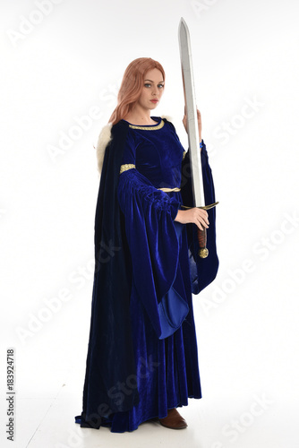  full length portrait of girl wearing long blue velvet gown and fur lined cloak, standing pose on white background.