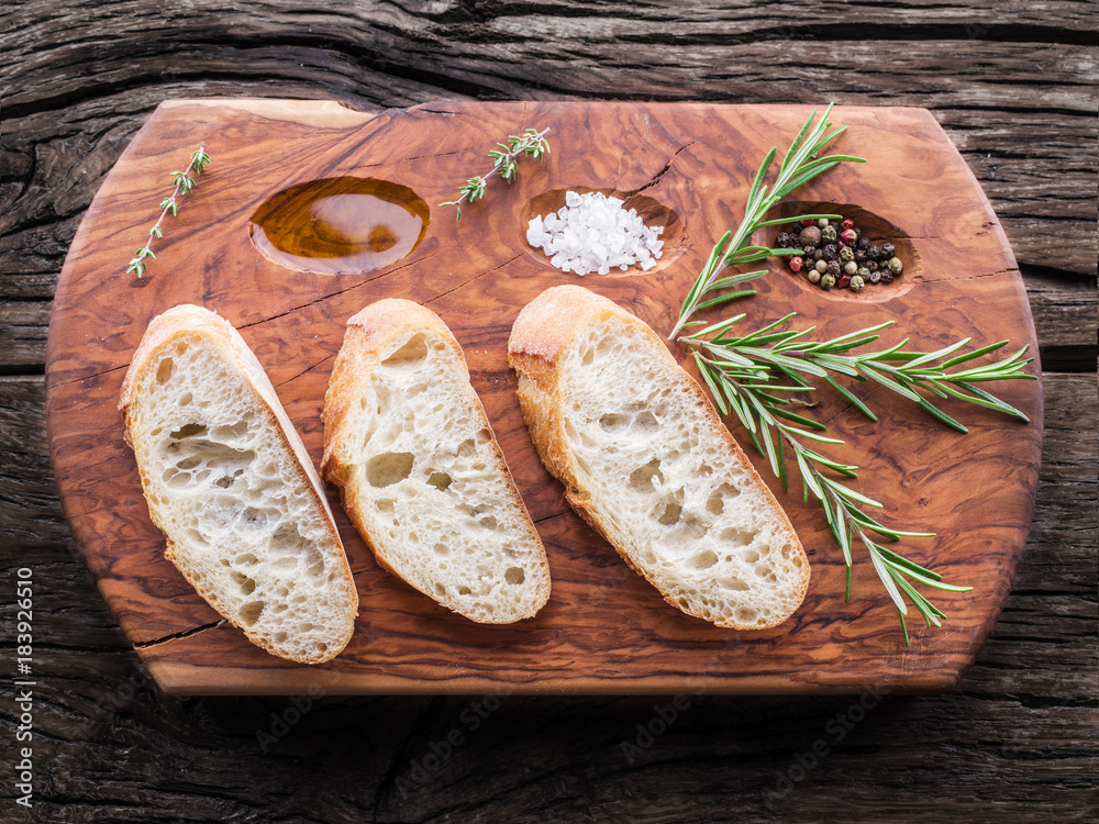 Slices of ciabatta with rosemary herb on the serving wooden tray Slices of ciabatta with rosemary herb on the serving wooden tray