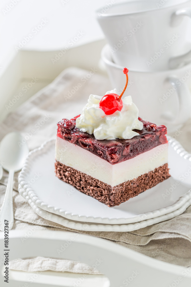 Tasty jelly cherry cake with cream on white plate