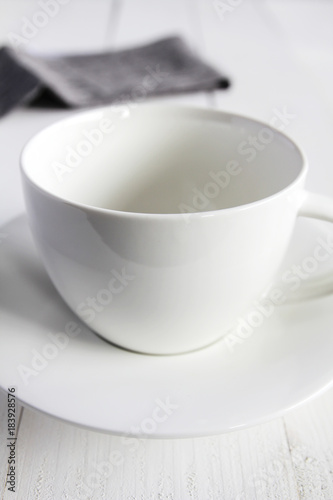 Empty white cup on white wooden table.