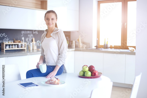 Fototapeta Naklejka Na Ścianę i Meble -  Happy woman drinking tea in the kitchen at home.