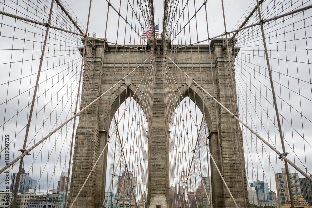Naklejka premium Close up architectural detail of the steel cable patterns leading to the traditional stone tower of the Brooklyn Bridge in New York City