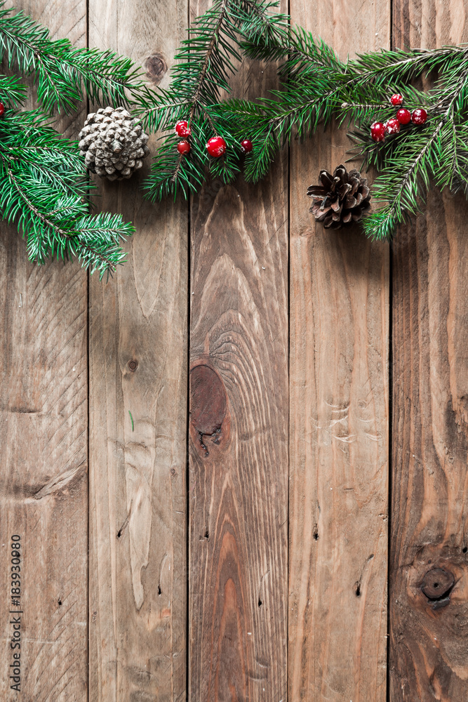 
A wooden background with sprigs of fir cones and cranberries. Christmas background.