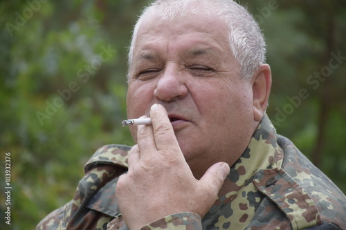 портрет курящего кавказского старика в лесу  