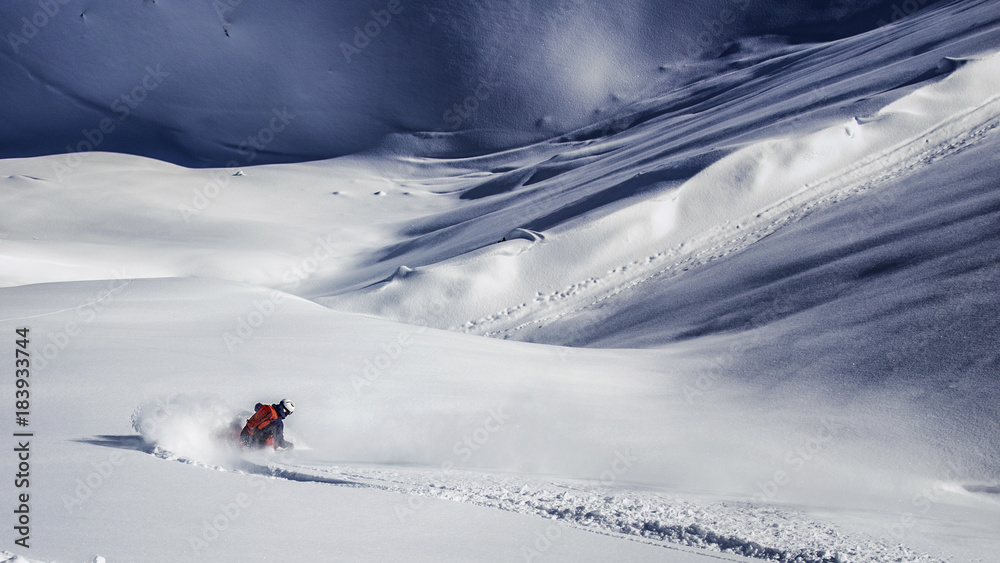 Freeride skier charging through powder snow