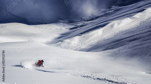Freeride skier charging through powder snow