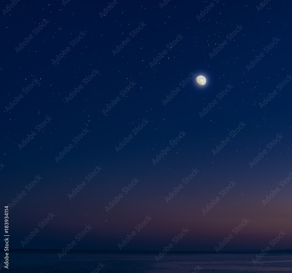 Moon and stars over the calm sea.