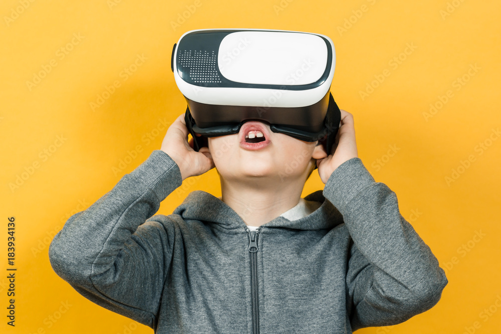 Boy with a headset of virtual reality. Innovative technology. On an orange background Boy with a headset of virtual reality. Innovative technology. On an orange background