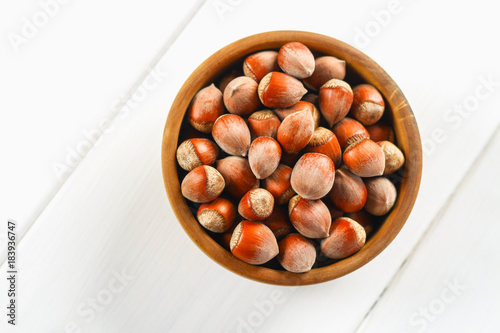 Hazelnut nuts in a wooden bowl on a white wooden table. Superfood.
