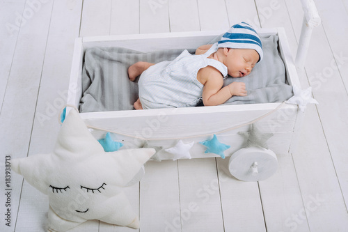 high angle view of cute newborn baby sleeping in wooden baby crib