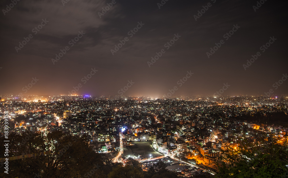 Panoramic view from Svayambunath stupa point of view on old sacred city of Kathmandu in night-time beam lighting.