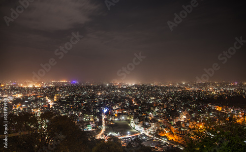 Panoramic view from Svayambunath stupa point of view on old sacred city of Kathmandu in night-time beam lighting.