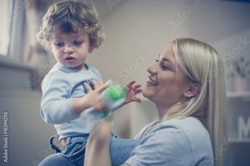 Young smiling mother playing with her baby boy.