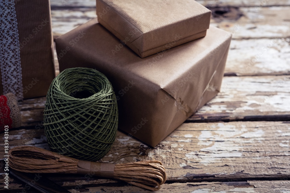 Gift boxes with wrapping material on wooden plank Gift boxes with wrapping material on wooden plank