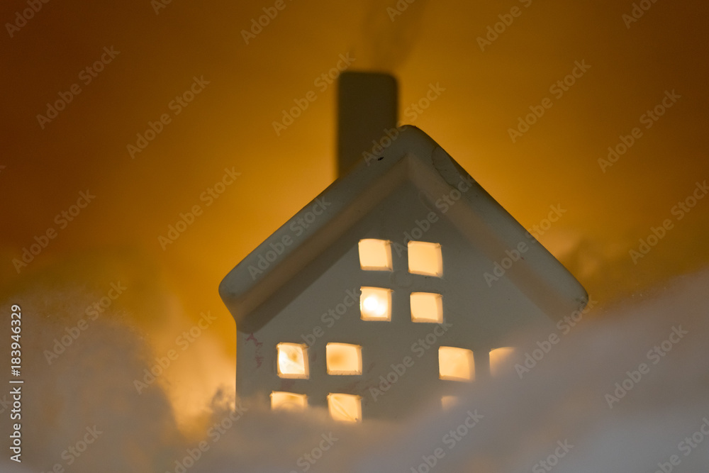 Toy model of a house with glowing warm windows and smoking chimney Toy model of a house with glowing warm windows and smoking chimney