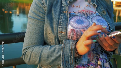 Pretty happy woman using smartphone in city park photo