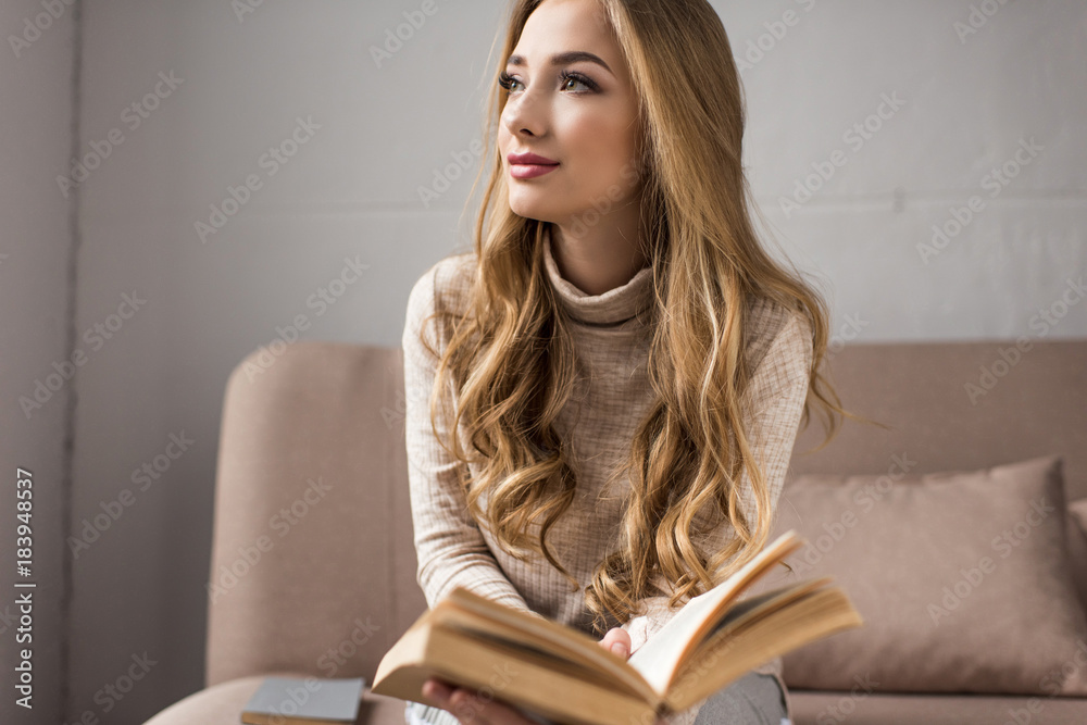 thoughtful young woman with book on cozy couch at home thoughtful young woman with book on cozy couch at home