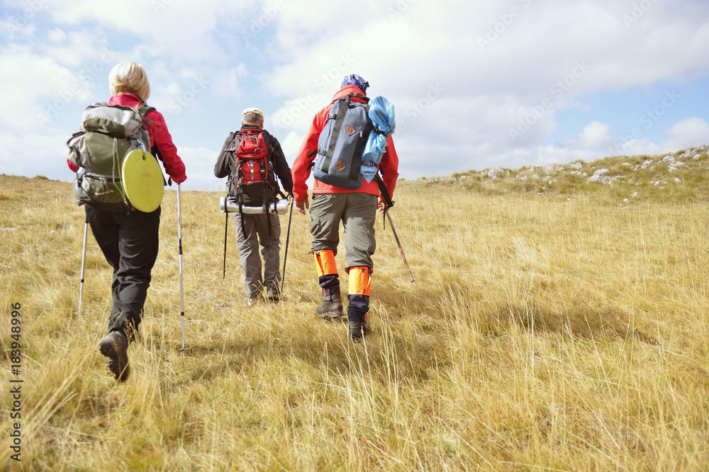 Group of tourists with backpacks on a mountain trail Group of tourists with backpacks on a mountain trail