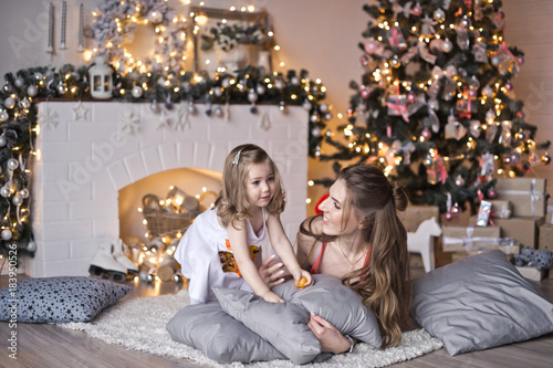 My daughter and her mother lying on the pillows around the Christmas tr © alenazamotaeva