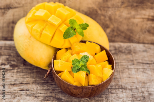 Mango fruit and mango cubes on the wooden table photo