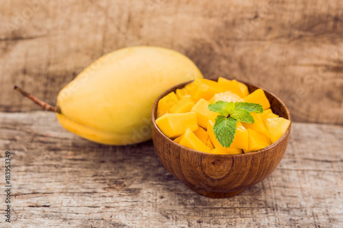 Mango fruit and mango cubes on the wooden table photo