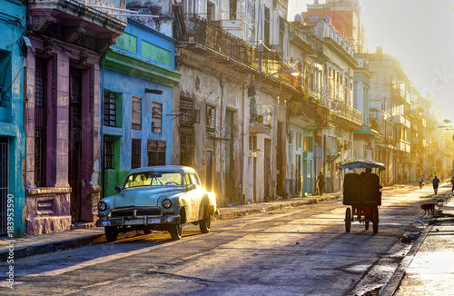 Street scene in Old Havana (La Habana Vieja), classic car, bicitaxi and people going to work, Cuba
