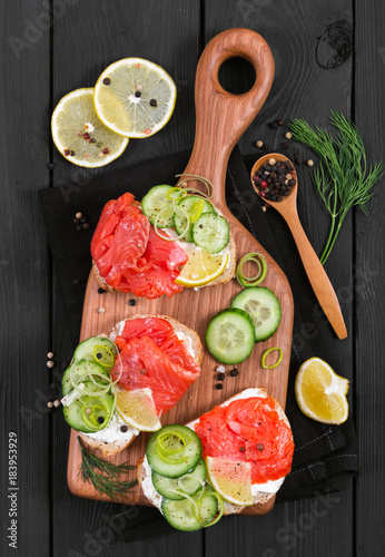 Fototapeta Naklejka Na Ścianę i Meble -  Bruschetta with salmon and fresh cucumber on cutting board